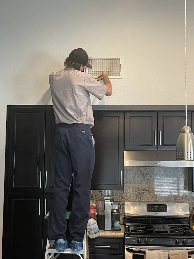 Technician inspecting an air vent during HVAC service in Brownsburg